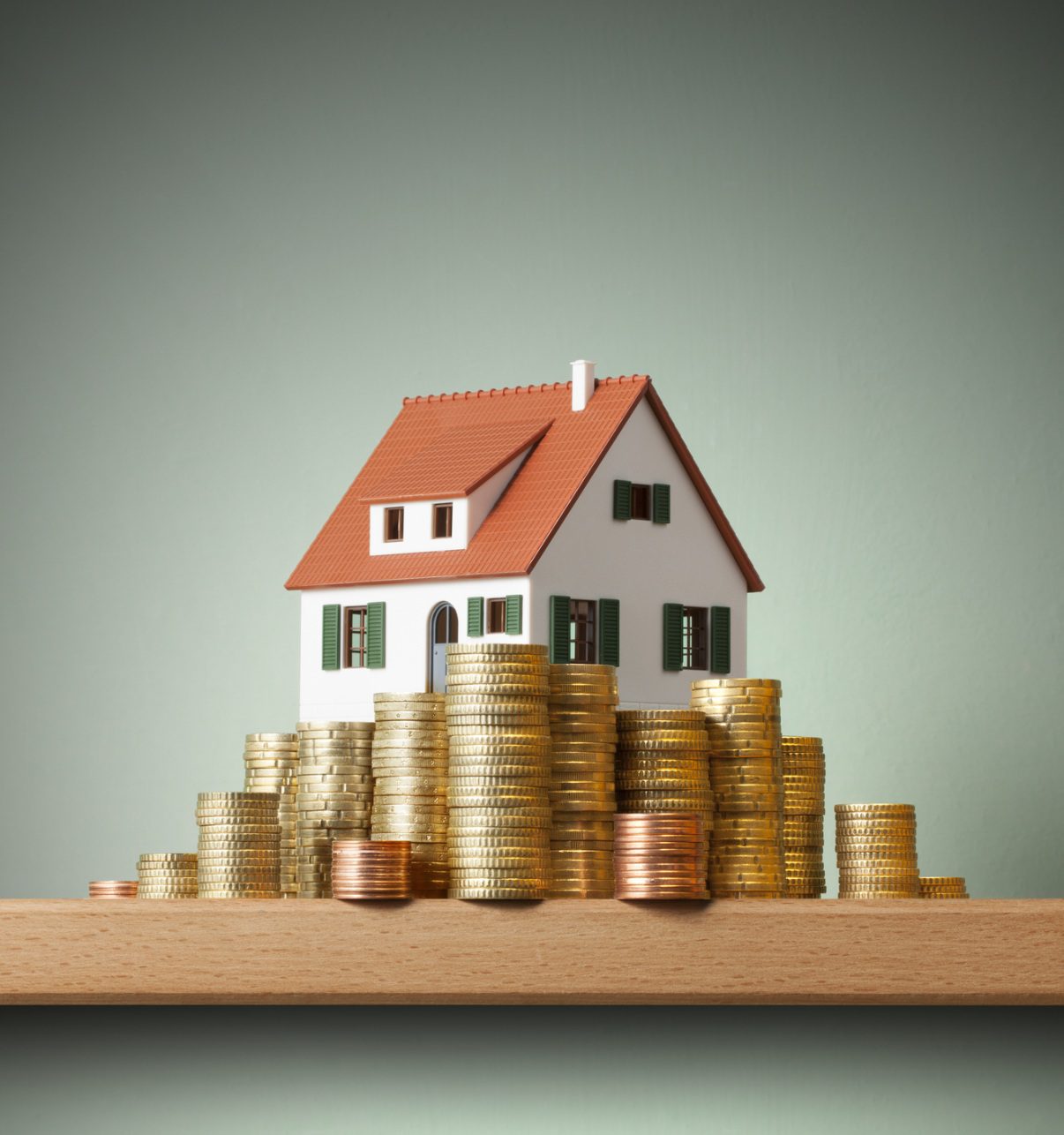 A house sitting on top of stacks of coins.