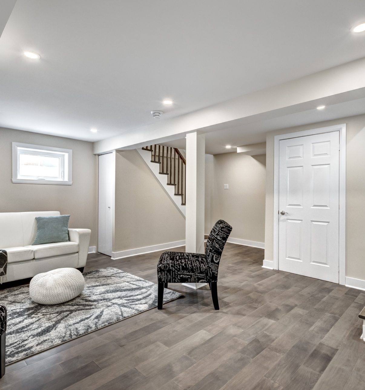 Finished basement with hardwood floors and seating.