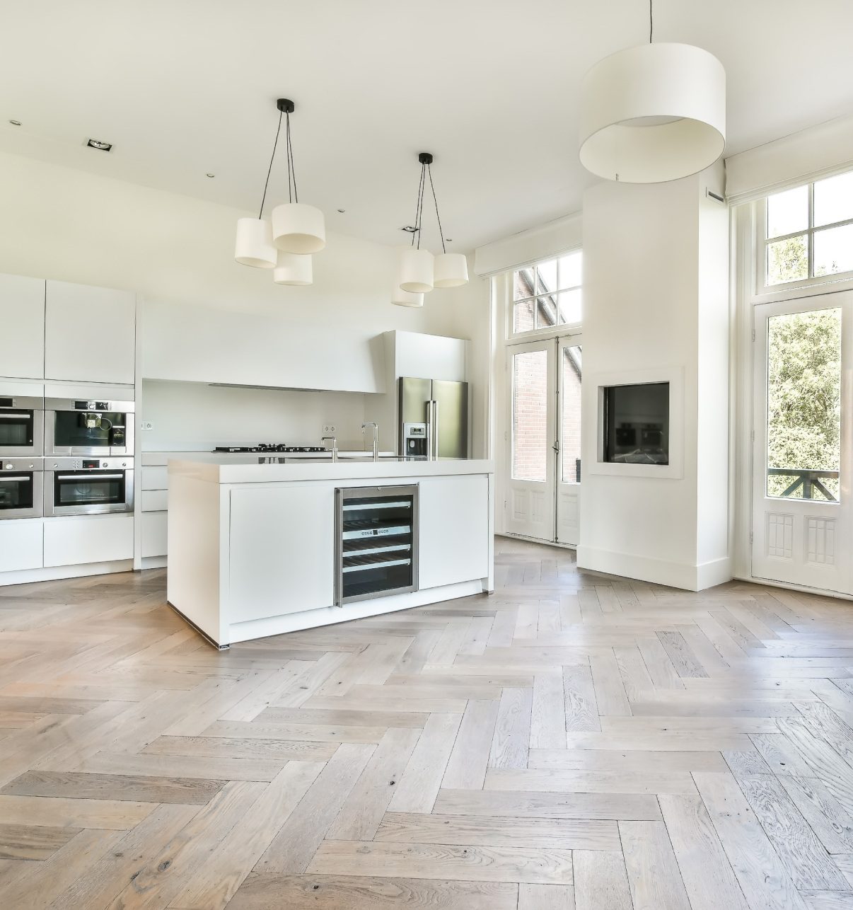 Modern white kitchen with herringbone floors.